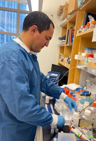 Team member Jesus in blue coat and blue gloves is working in the lab
